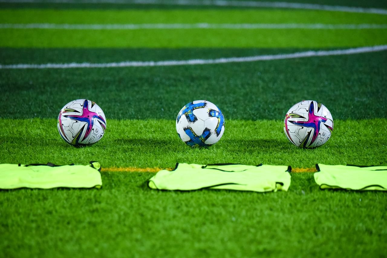 Bolas de futebol no gramado antes do treino, ilustrando como fazer um palpite de futebol